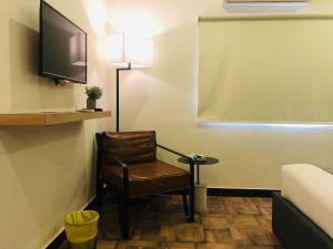 a room with a chair and a tv and a table at OBAN Hotel in Lahore