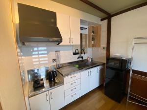 a kitchen with white cabinets and a sink and a microwave at guesthouse Yokomachi in Shingu