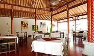 a dining room with tables and chairs in a building at Agung Trisna Bungalows in Ubud