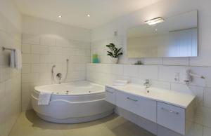a white bathroom with a tub and a sink at Hotel Sternenlicht in Löhne