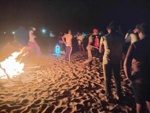a group of people standing around a fire on a beach at 20 House Villa in Arugam Bay