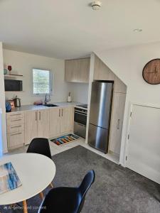 Una cocina con refrigerador de acero inoxidable y una mesa. en Beachside Townhouse, en Christchurch