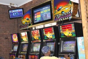 a man standing in front of a bunch of video games at Corroboree Park Tavern in Marrakai