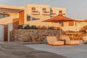 a patio with two chairs and an umbrella at Aelo Mykonos Hotel in Paradise Beach