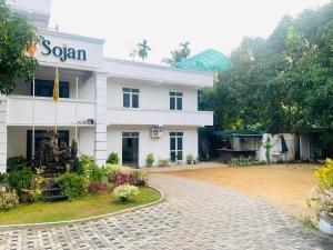 a white building with a sign on the side of it at Hotel Sojan in Veyangoda