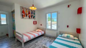 two beds in a room with two windows at Jolie maison rénovée sur Loix in Loix