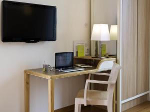 une pièce avec un bureau avec un ordinateur portable et une télévision dans l'établissement Aparthotel Adagio Paris Vincennes, à Vincennes