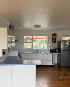 a kitchen with white cabinets and a stainless steel refrigerator at The Seaside Escape- Cozy 2BR by the sea in Tinderbox