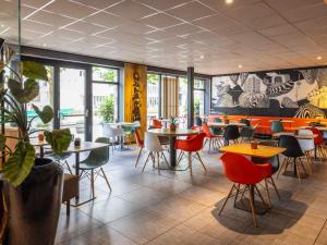 a restaurant with tables and chairs and windows at ibis Rotterdam City Centre in Rotterdam