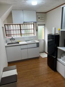 a kitchen with white cabinets and a black refrigerator at 湯本早雲 in Hakone