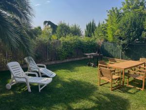 a yard with chairs and a wooden table and a table and chairs at Las Candelas, Casa Turística in Uruñuela