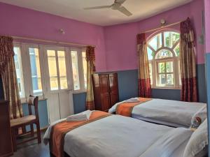 een slaapkamer met twee bedden en een raam bij Hotel Fishtail Villa in Pokhara