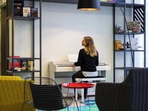 a woman sitting at a piano in a room at Aparthotel Adagio Köln City in Cologne