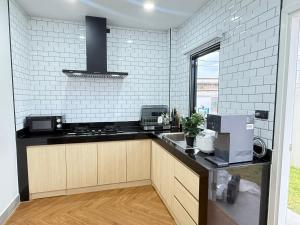 a kitchen with a black counter top and white tiles at Phupha house Hatyai in Sathani Khlong Rian