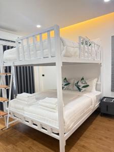 a bunk bed with white bunk beds in a room at Phupha house Hatyai in Sathani Khlong Rian