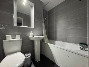 a bathroom with a toilet and a sink and a tub at Jessie Terrace Stays in Southampton +7 photos