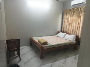 a small bedroom with a bed and a chair at Devi Palace Pattabiram in Tandurai +6 photos