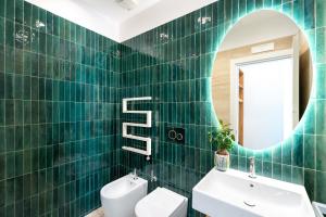 a bathroom with green tiled walls and a mirror at Domus Gualtieri in Sorrento