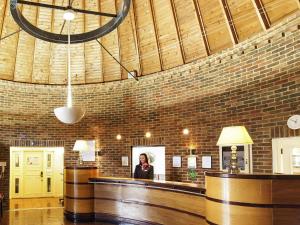 a woman standing at a bar in a brick room at Mercure Tunbridge Wells Hotel in Royal Tunbridge Wells