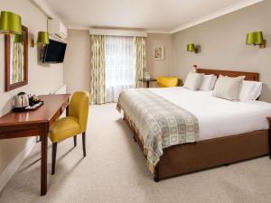 a hotel room with a bed and a desk at Mercure Gloucester Bowden Hall Hotel in Gloucester