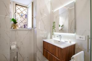 Un baño blanco con lavabo y espejo. en Aras Luxury Flat, en Roma 42 fotos más
