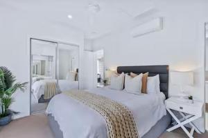 a white bedroom with a large bed and a mirror at Park Avenue Terrace 1BR, 4km to CBD, WiFi, Park in Brisbane