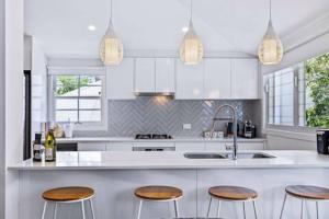 a white kitchen with three stools and a sink at Park Avenue Terrace 1BR, 4km to CBD, WiFi, Park in Brisbane +8 photos