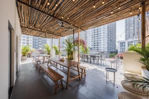 un patio con mesas y bancos en un balcón en The Amethyst Nest Hanoi-Tranquil Stay with Rooftop & Coffee Shop-Near Old Quarter, en Hanói