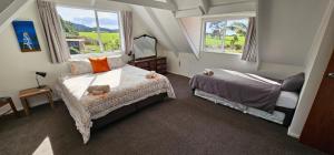 a bedroom with a bed and a table and two windows at Soggy Bottom Farm House, Sea views and peacocks in Pakawau