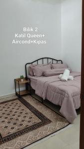 a bedroom with a bed with pink sheets and a rug at D'Raudhah Homestay Binjai Kemaman  +2 photos
