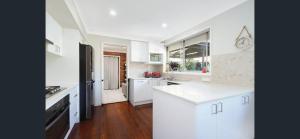 a kitchen with white cabinets and a black refrigerator at Private room with pool and ensuite in Campbelltown South