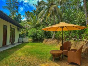 a table and chairs under an umbrella in a yard at Serene View Lodge in Unawatuna