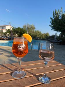 two glasses of wine and an orange slice on a wooden table at Villa Sofia in ayios Petros