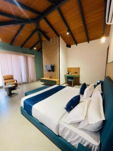 a bedroom with a large bed with blue and white pillows at Sahyadri Farms agro tourism-Villa and cottages 