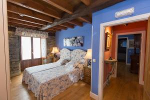 a bedroom with a bed with blue walls and wooden floors at Hotel Rural Casa Xusto in La Caridad