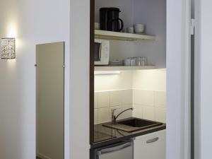 a kitchen with a sink and a counter top at Aparthotel Adagio Access Paris Philippe Auguste in Paris +30 photos