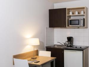 a small kitchen with a table and a microwave at Aparthotel Adagio Access Paris Clamart in Clamart