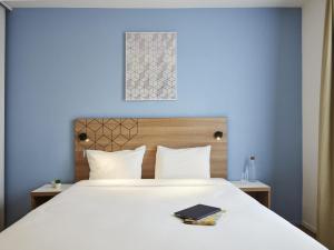 a bedroom with a white bed with a blue wall at Aparthotel Adagio Access Paris Quai d'Ivry in Ivry-sur-Seine