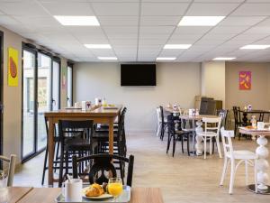 a dining room with tables and chairs and a tv at Aparthotel Adagio Access Rennes Centre in Rennes
