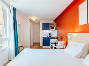 a bedroom with a white bed and a kitchen at Aparthotel Adagio Access Paris Saint-Denis Pleyel in Saint-Denis +51 photos
