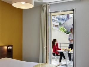 Un hombre y una mujer sentados en una mesa en una habitación de hotel. en Aparthotel Adagio Access Poitiers, en Poitiers