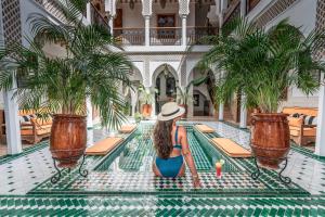 a woman in a hat sitting in a pool at a hotel at Riad NL&S Collection in Marrakech