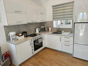 a white kitchen with white cabinets and appliances at Nerea in Agia Effimia