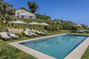 an image of a swimming pool with chairs and umbrellas at Villa Petra in Capodarco