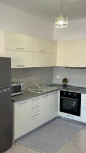 une cuisine avec des armoires blanches, un évier et un micro-ondes dans l'établissement Labeat Apartment, à Shkodër