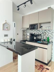 a kitchen with white cabinets and black counter tops at Dream Nook - One Bedroom Apt in Tatu City in Tatu City +10 photos