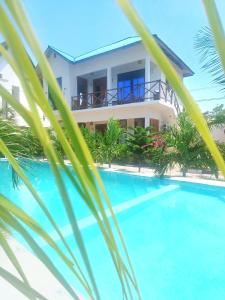 una casa con piscina y palmeras en Sailorvilla and apartments, en Jambiani