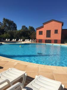 une piscine avec des chaises blanches et un bâtiment dans l'établissement Chez Valérie et Stéphane, Les terrasses de Lozari, à Belgodère 18 autres photos