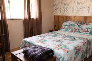 a bedroom with a bed with a floral comforter at Apto Aconchegante Na Cidade do Café in Brejetuba