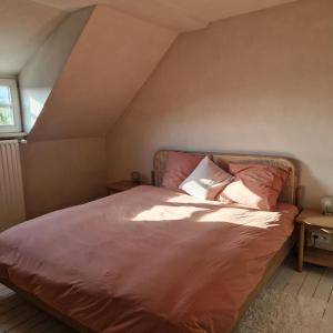 WingeneにあるAuthentiek vakantiehuis Bos-en-Veldのピンクのシーツが敷かれたベッドと窓のある寝室